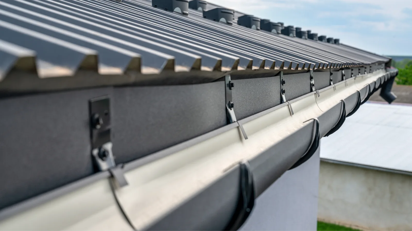 Metal roof edge with brackets securing a half-round gutter